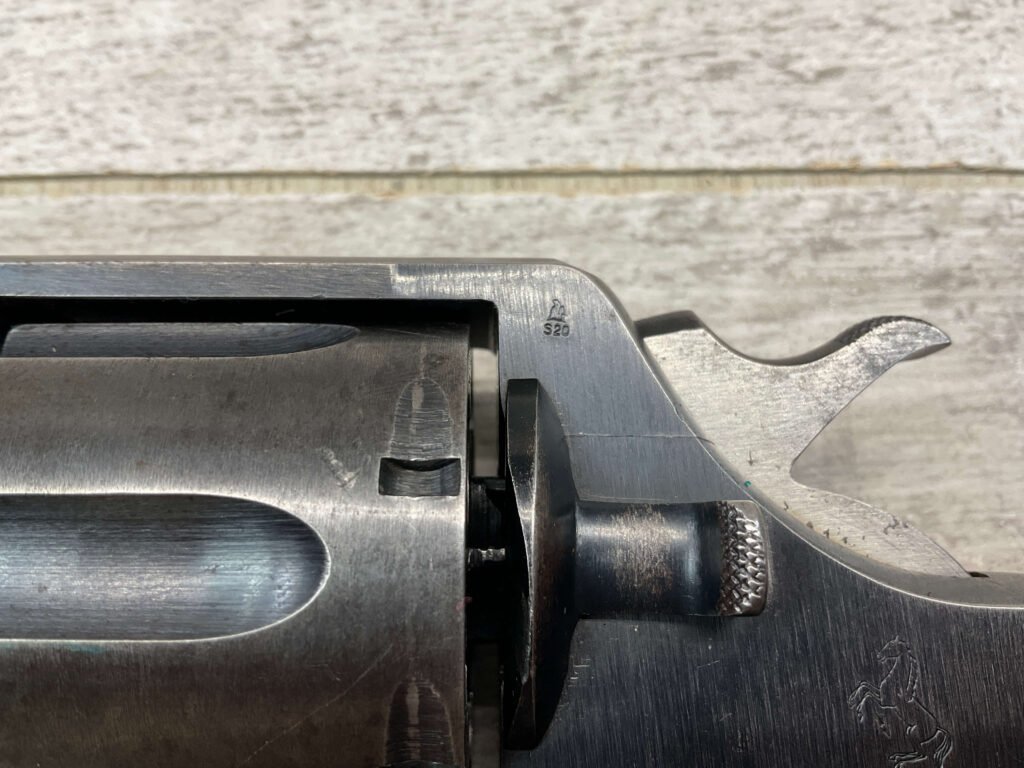 Metal gun with engraved horse logo, focus on firearms detail, close-up shot; ideal for historical or military-themed content.