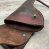 Vintage leather holster with a brass button, showing signs of aging, on a wooden surface. An authentic piece of historical military equipment, reflecting classic craftsmanship and design.