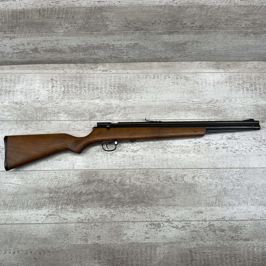 Model air rifle with wooden stock and metal barrel, displayed on a rustic wooden surface. Perfect for collectors or enthusiasts interested in historical or replica firearms.