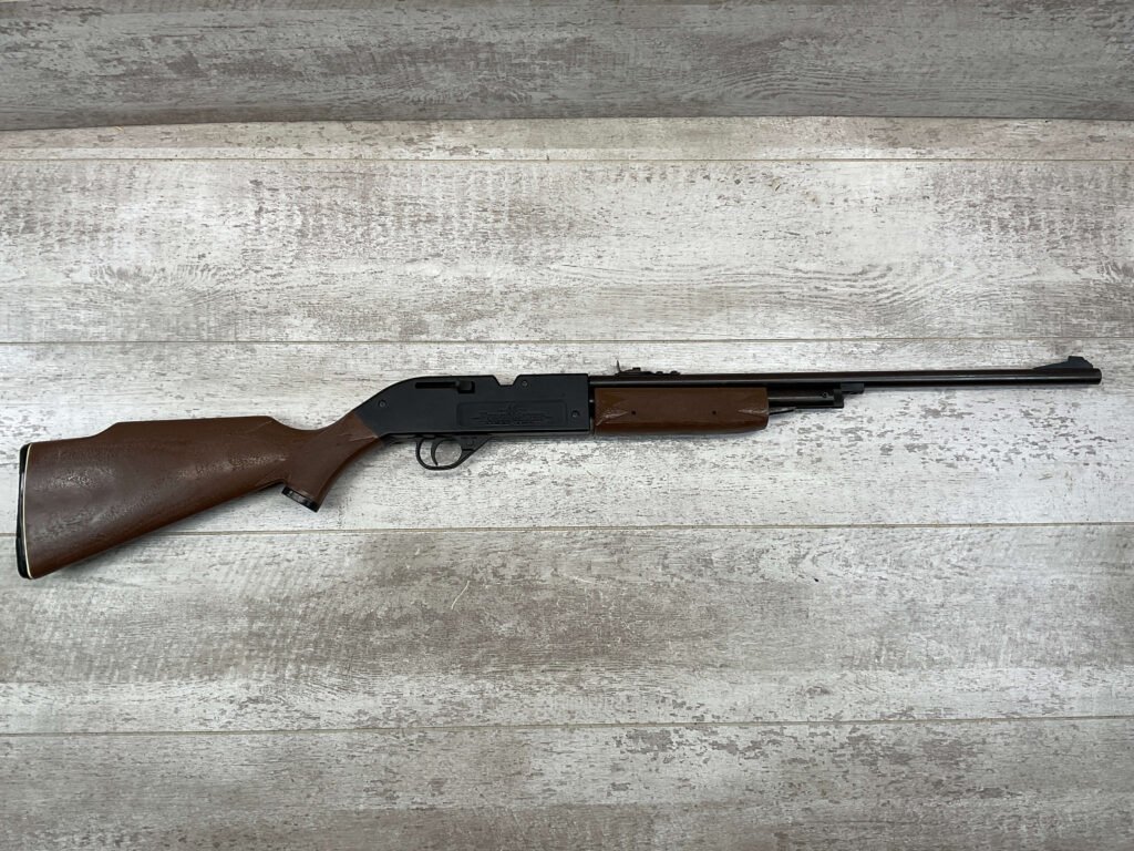 Firearm replica of a rifle or shotgun laying on a wooden surface, used for display or decoration at Checkpoint Charlie's, a famous Berlin historical site and tourist attraction.