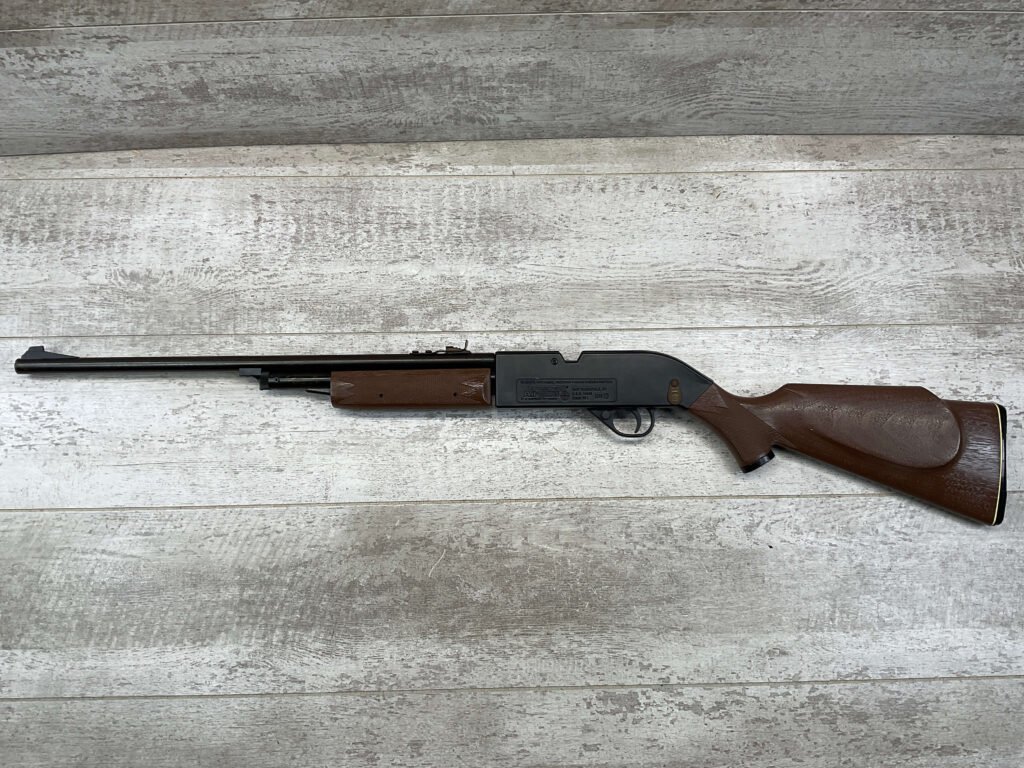 Vintage air rifle with wooden stock on light wooden background.