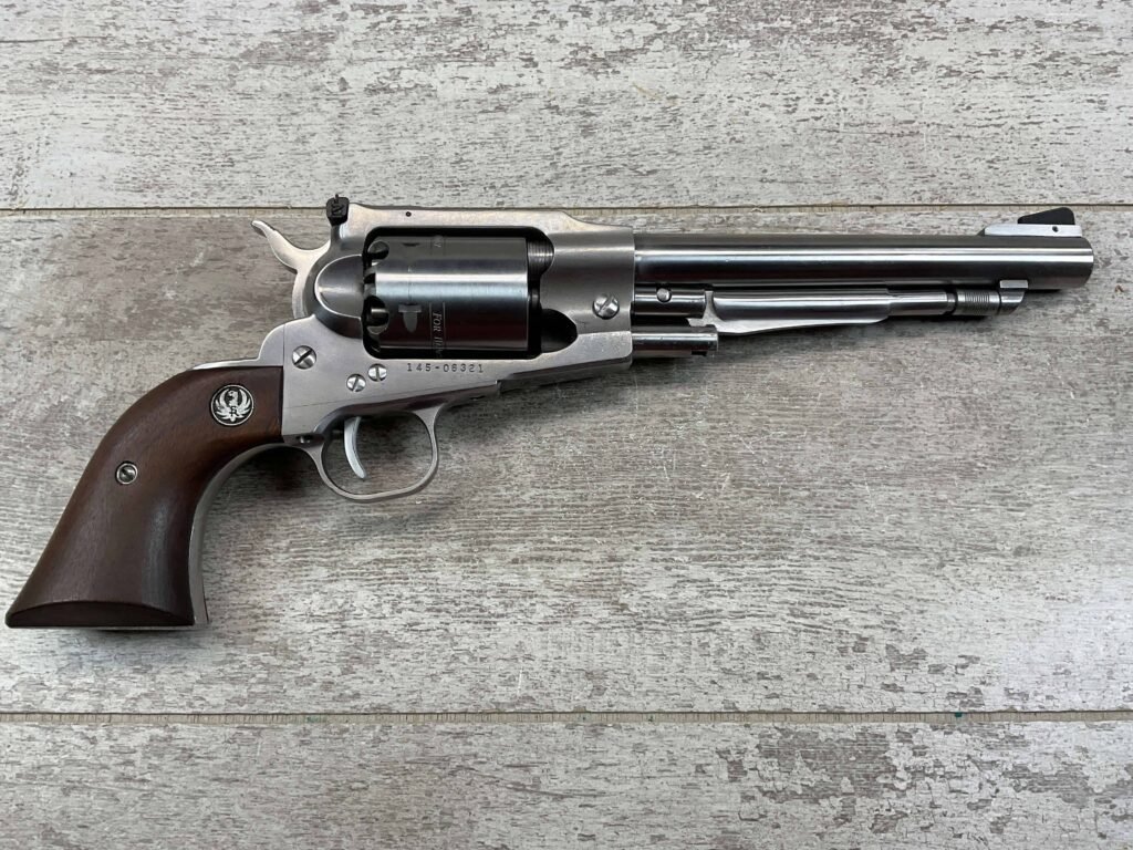 A vintage revolver with a wooden grip and metal barrel, displayed on a rustic wooden surface at Checkpoint Charlie, Berlin.