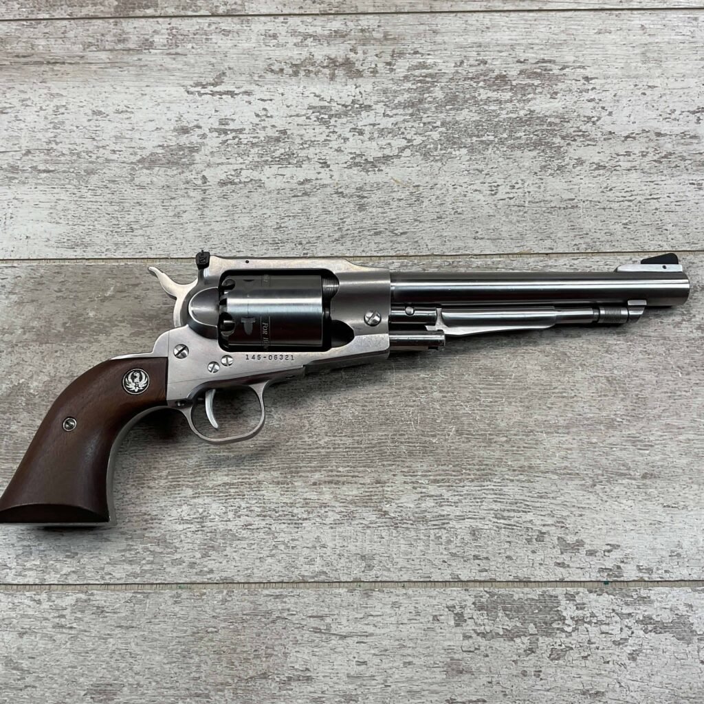 A stainless steel revolver with wooden grip, laid on a weathered wooden surface. The firearm features a long barrel and detailed craftsmanship, typically associated with collectible or firearm enthusiasts.