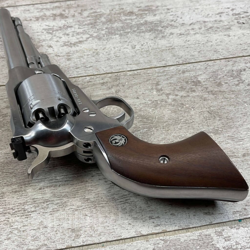 Sleek silver revolver with wooden grip, detailed metal finish, on a rustic wooden surface. A symbol on the grip suggests a classic firearm with a polished, vintage appearance, often associated with historical or collectible weapons.