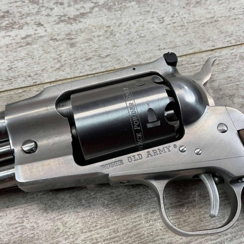 4. A close-up image of a silver Ruger Old Army revolver with "Black Powder Only" engraved on the cylinder, resting on a wooden surface, showcasing its metallic finish and detailed craftsmanship.