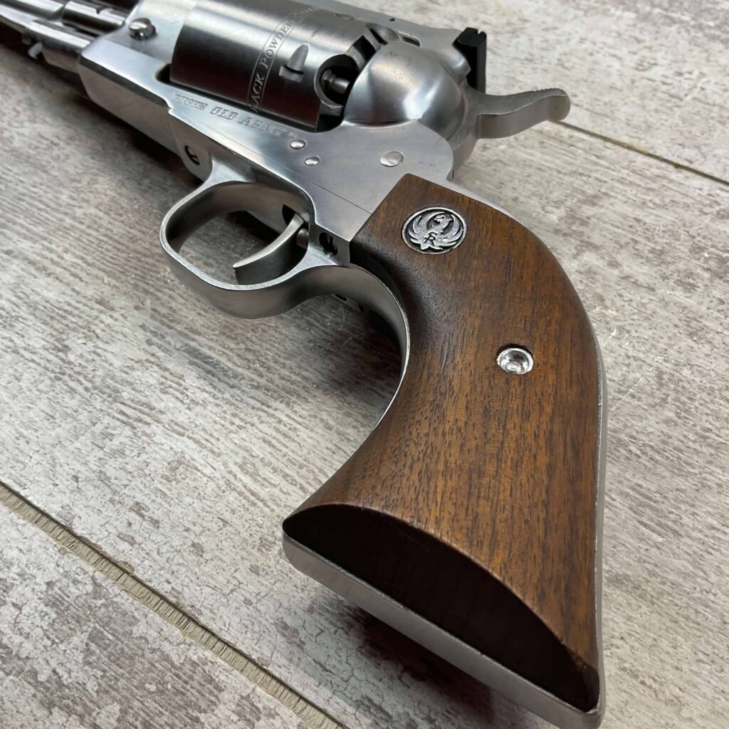 Metal revolver with wooden grip on wooden surface, close-up of a firearm, firearm image, collectible handgun, revolver for display or collection.